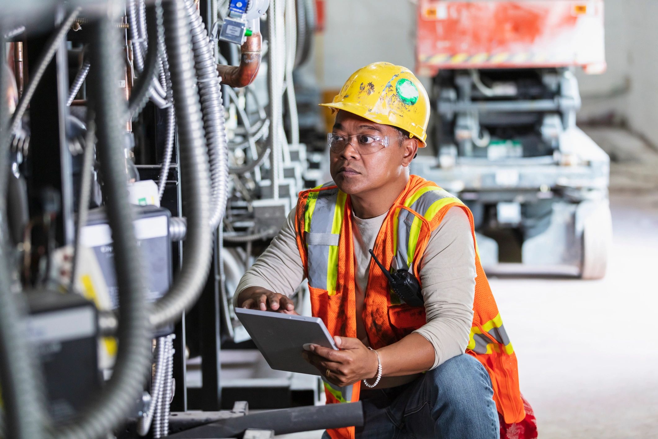 Technician inspecting industrial equipment while using a rugged tablet