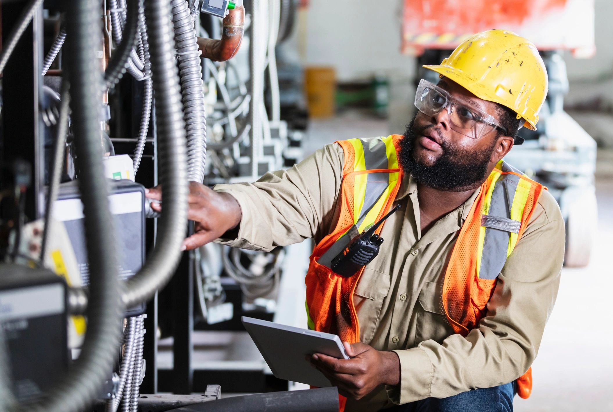 Technician inspecting industrial equipment while using a tablet