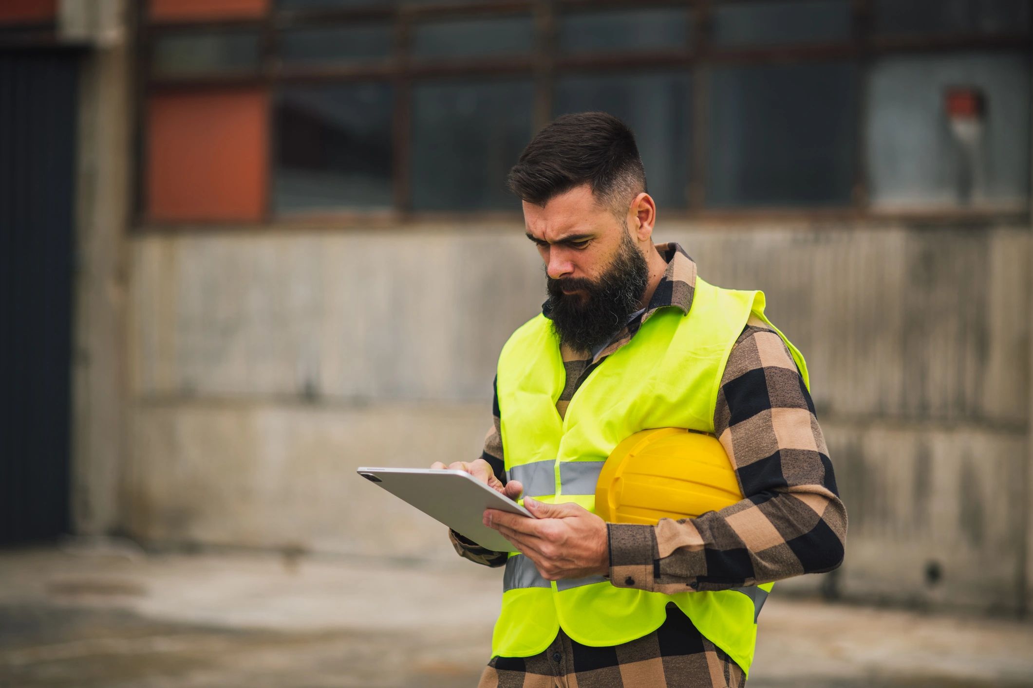 Field worker reviewing tasks on a tablet near industrial vehicles